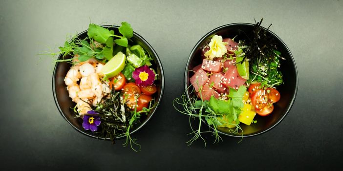 Poke salads with tuna and beef in bowls on the table. Two bowls of poke salad with chopsticks on a gray background. Asian seafood salad concept.