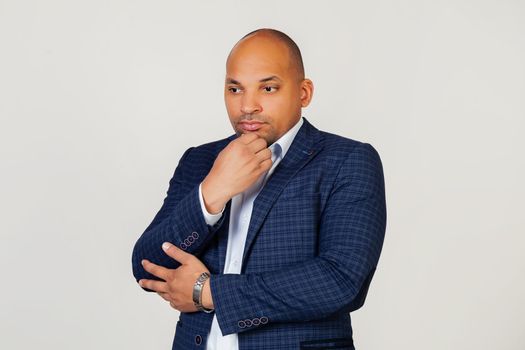 Portrait of an unhappy young African American guy businessman, thinking looking tired and bored with depression problems with crossed arms. Standing on a gray background