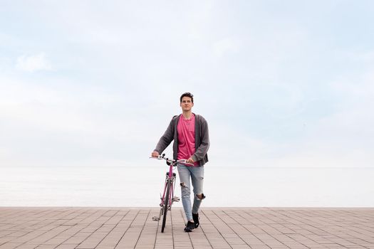 front view of a young student walking while pushing a bike, concept of ecological and sustainable transportation, copy space for text