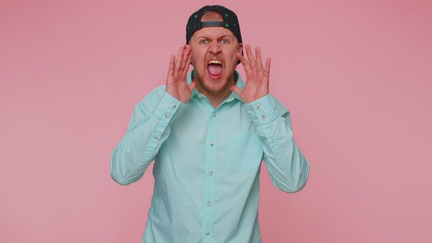 Expressive man holding hands near mouth loudly screaming, shouting, yelling, announces discounts sale Hurry up, welcomes someone hello. Young adult guy isolated alone on pink studio wall background