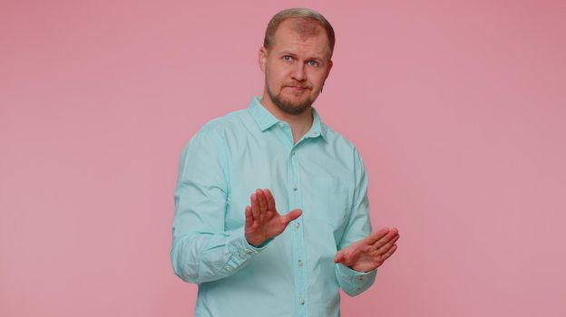 Hey you, be careful. Man warning with admonishing finger gesture, saying no, be careful, scolding and giving advice to avoid danger, disapproval sign. Young guy isolated on pink studio wall background
