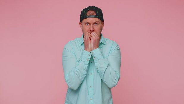 Panic attack. Upset scared frightened bearded adult man biting nails, feeling worried nervous about serious troubles, stress and anxiety disorder, guilty. Young one guy on pink studio wall background