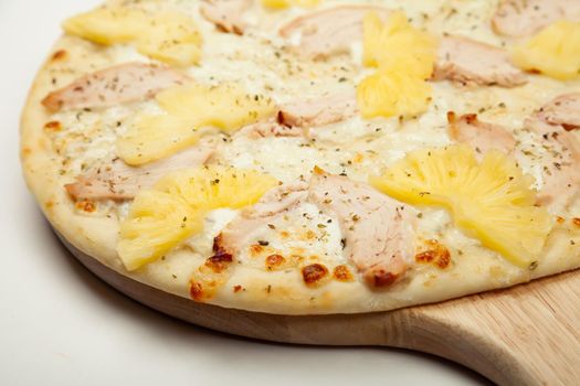 Texture Delicious Hawaiian pizza served on a wooden plate, ingredients garlic sauce, mozzarella cheese, smoked chicken, canned pineapples on white. Pizzeria promotion poster.