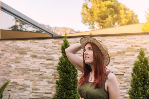 young woman relaxing, looking at the blue sky, sunbathing in the sun on a summer day. woman enjoying her holiday in the hotel garden. Outside, dim sunlight, grass floor with white tiles.