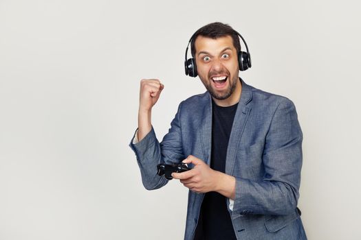 European male gamer playing a video game with headphones on an isolated white background annoyed and upset screams with anger, crazy and shouts with his hand raised, anger of the concept