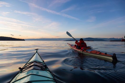 Adventure Man on a Sea Kayak is kayaking during a vibrant and colorful winter sunset. Taken in Vancouver, British Columbia, Canada. Adventure, Vacation Concept