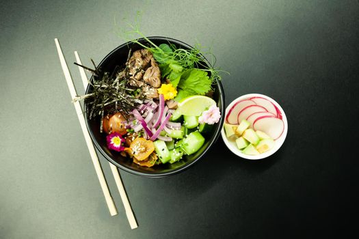 Poke salad with beef in a bowl. Ingredients Beef, Nameko mushrooms, cherry tomatoes, rice, cucumber, red onion, Kim Chi sauce, Ponzu sauce, nori, sesame seeds, cilantro, lime. Asian salad concept.