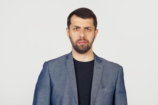 Young businessman man with a beard in a jacket, skeptical and nervous, frowning, upset because of the problem. Negative person. Portrait of a man on a gray background.