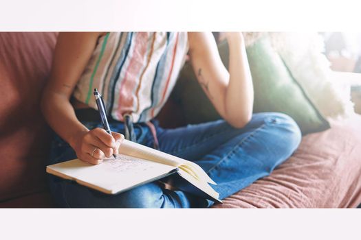 Cropped shot of a young woman making notes while relaxing on the sofa at home stock photo
