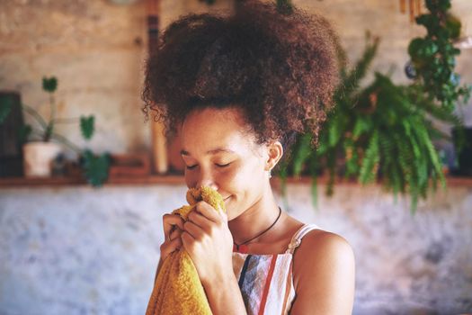 Shot of a beautiful African woman smelling freshly washed laundry while at home - Stock Photo