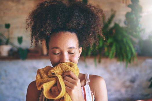 Shot of a beautiful African woman smelling freshly washed laundry while at home - Stock Photo