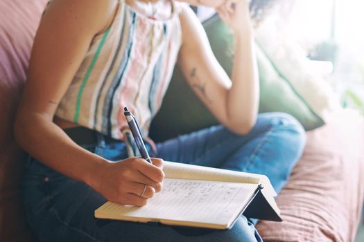 Shot of a unrecognizable woman making notes while relaxing on the sofa at home stock photo