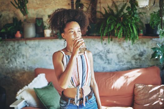 Shot of a beautiful African woman drinking medication in her living room - Stock Photo