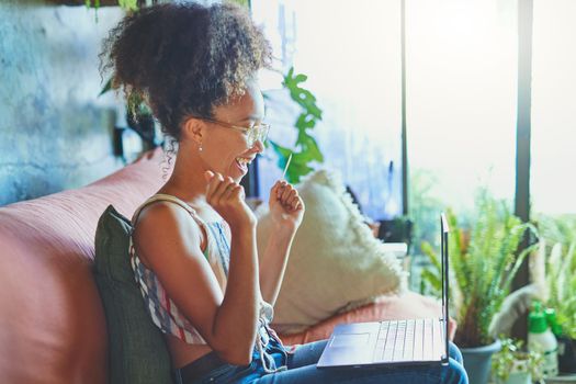 Shot of a beautiful African woman being cheerful on her couch