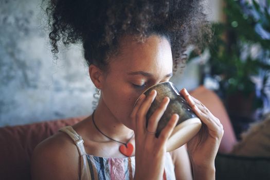 Shot of a beautiful African young woman enjoying a cup of coffee - Stock Photo