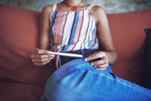 Cropped Shot of a young woman taking a pregnancy test on the sofa at home stock photo