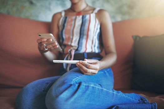 Shot of a young woman taking a pregnancy test on the sofa at home stock photo