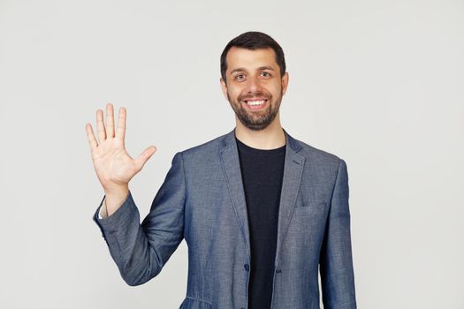 Young businessman man with beard smiling, showing number five with fingers on hand, smiling confidently and happily, looking into the camera. The man shows five fingers. Number 5.