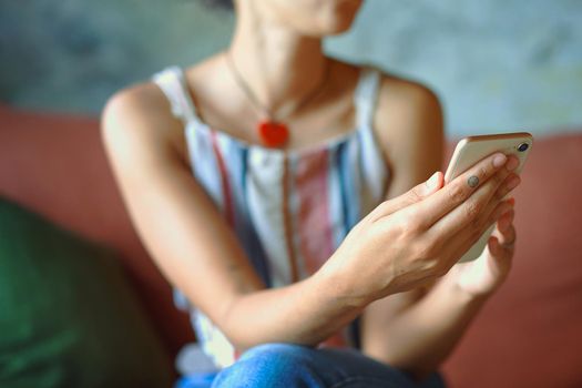 Cropped shot of a young woman using a cellphone while relaxing on a sofa at home