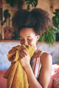 Shot of a beautiful African woman smelling freshly washed laundry while at home - Stock Photo