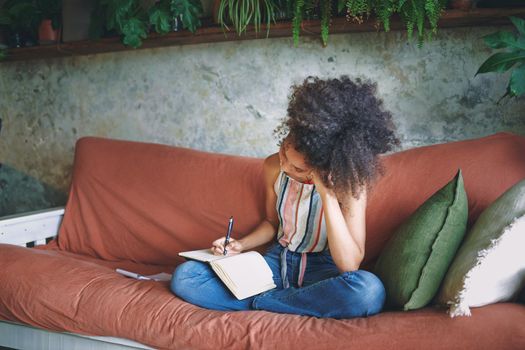 Shot of a young woman making notes while relaxing on the sofa at home stock photo