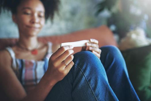 Shot of a young woman taking a pregnancy test on the sofa at home stock photo