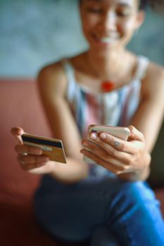 Cropped shot of a young woman using a cellphone while relaxing on a sofa at home