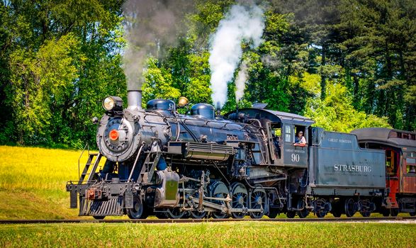 Ronks, Pennsylvania, May 20, 2010 - An Antique Steam Passenger Train Approaching on a Single Track Blowing Smoke on a Sunny Day