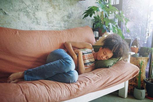 Shot of a young woman experiencing stomach pain while lying on the sofa at home stock photo