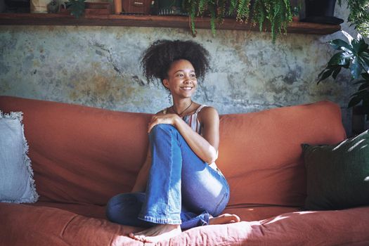 Shot of a beautiful African young woman relaxing on her sofa at home - Stock Photo