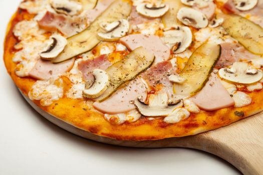 Delicious Meat pizza served on a wooden plate, ingredients Signature sauce, mozzarella cheese, ham, bacon, pickled cucumber, mushrooms on white. Pizzeria promotion poster.