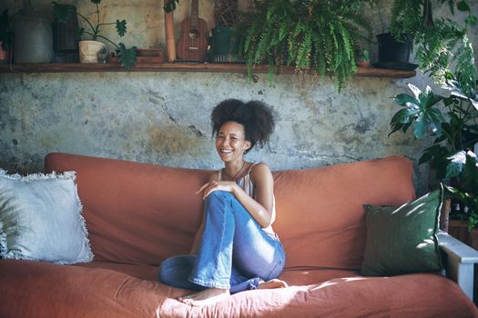 Shot of a beautiful African young woman relaxing on her sofa at home - Stock Photo