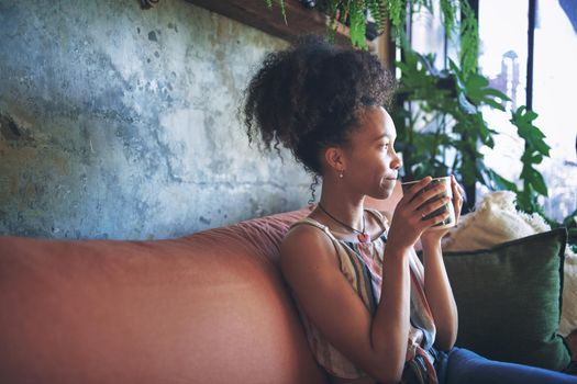 Shot of a beautiful African young woman enjoying a cup of coffee - Stock Photo