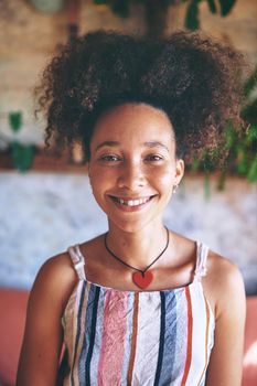 Portrait of a beautiful African woman smiling at the camera while at home in her living room - Stock Photo