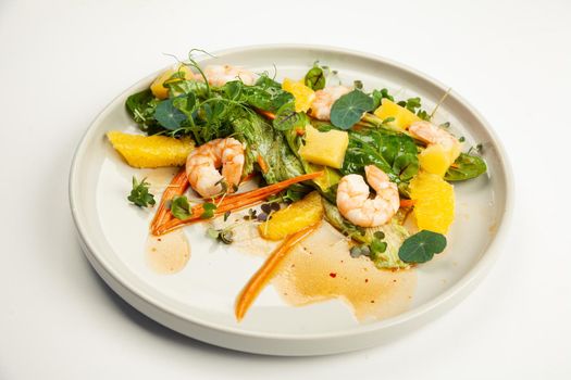 Shrimp salad in soy-ginger dressing on a plate. Ingredients Iceberg lettuce, shrimp, spinach, orange, pineapple, carrot, soy-ginger dressing. For restaurant menu.