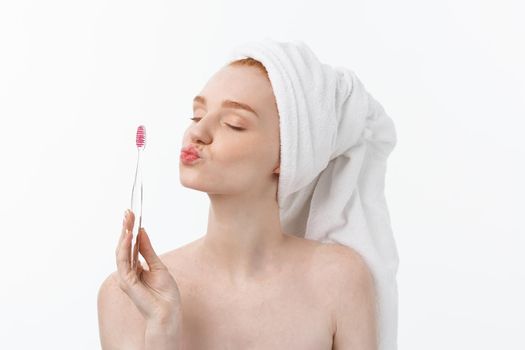 Portrait of young woman with toothbrush on grey background