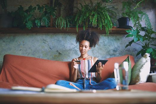 Shot of a beautiful African woman doing online shopping from her living room