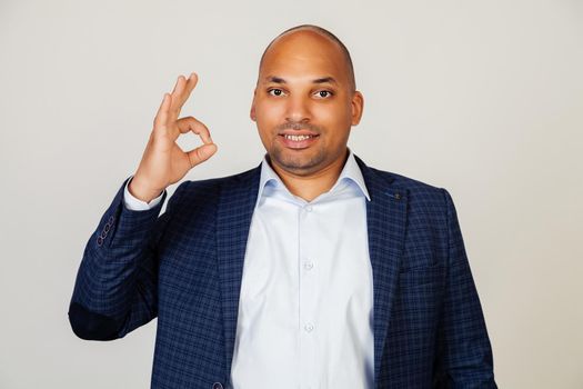 Young african american man smiling positively, making okay hand and fingers sign. Lucky expression. Black man feeling successful and contented, smiling making a sign ok with his hand.