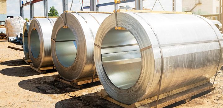 Stainless steel rolls. Rolls of steel sheet in the warehouse. A roll of galvanized steel sheet for the production of metal pipes and tubes in a factory