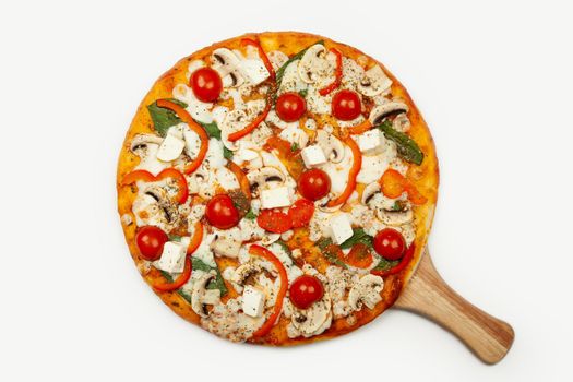 Delicious Vegetarian pizza served on a wooden plate, the ingredients are signature sauce, basil, mozzarella cheese, champignons, bell peppers, cherry tomatoes, feta cheese. Pizzeria promotion poster.