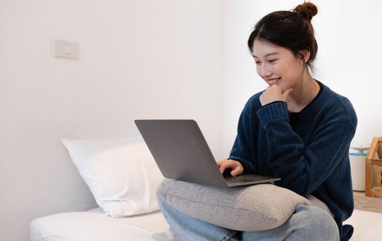 Portrait of young asian woman resting with laptop at home, sitting on couch in modern living room..