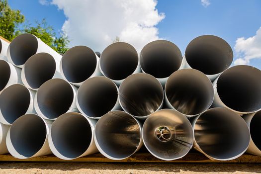 Downpipe warehouse. Steel pipes, parts for the construction of a roof drainage system in a warehouse. Stack of stainless steel pipes