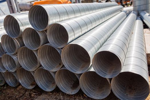 Ventilation pipes against the blue sky. Steel pipes, parts for the construction of air ducts for an industrial air conditioning system in a warehouse. Industrial ventilation equipment
