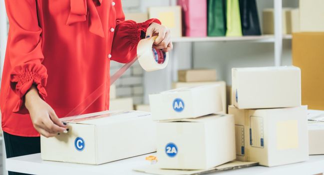 Online seller works at home office and packs shipping delivery box to customer. Small business owner or entrepreneur doing e-commerce business on the internet.