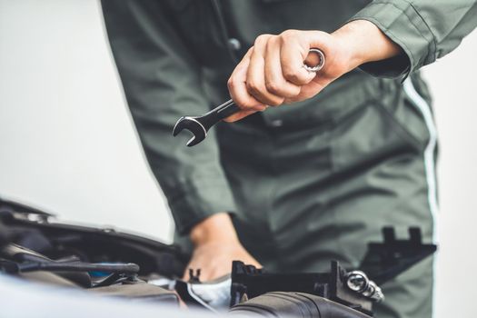 Professional mechanic hand providing car repair and maintenance service in auto garage. Car service business concept.