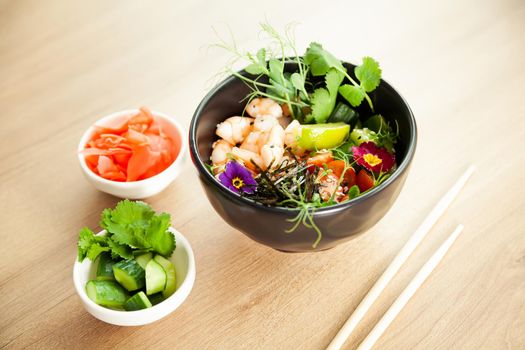 Poke salad with shrimp in a bowl. Ingredients Shrimp, blanched spinach, cherry tomatoes, rice, cucumber, soy-ginger sauce, Spicy sauce, nori, sesame, lime, cilantro. Asian seafood salad concept