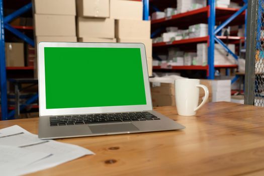 Computer with green screen display in warehouse storage room . Delivery and transportation software concept .