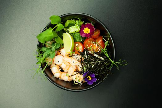 Poke salad with shrimp in a bowl. Ingredients Shrimp, blanched spinach, cherry tomatoes, rice, cucumber, soy-ginger sauce, Spicy sauce, nori, sesame, lime, cilantro. Asian seafood salad concept