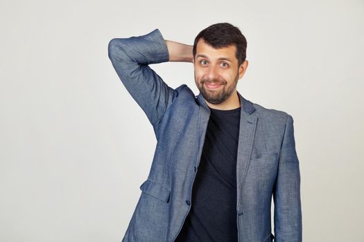 Young businessman with a smile, man with a beard in a jacket, worried about a problem, with a hand on his head, nervous and worried about the crisis, Portrait of a man on a gray background