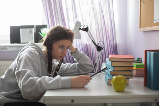 A girl sits at her desk and wonders how she will read all those school readings during the school year. A young girl with pigtails.